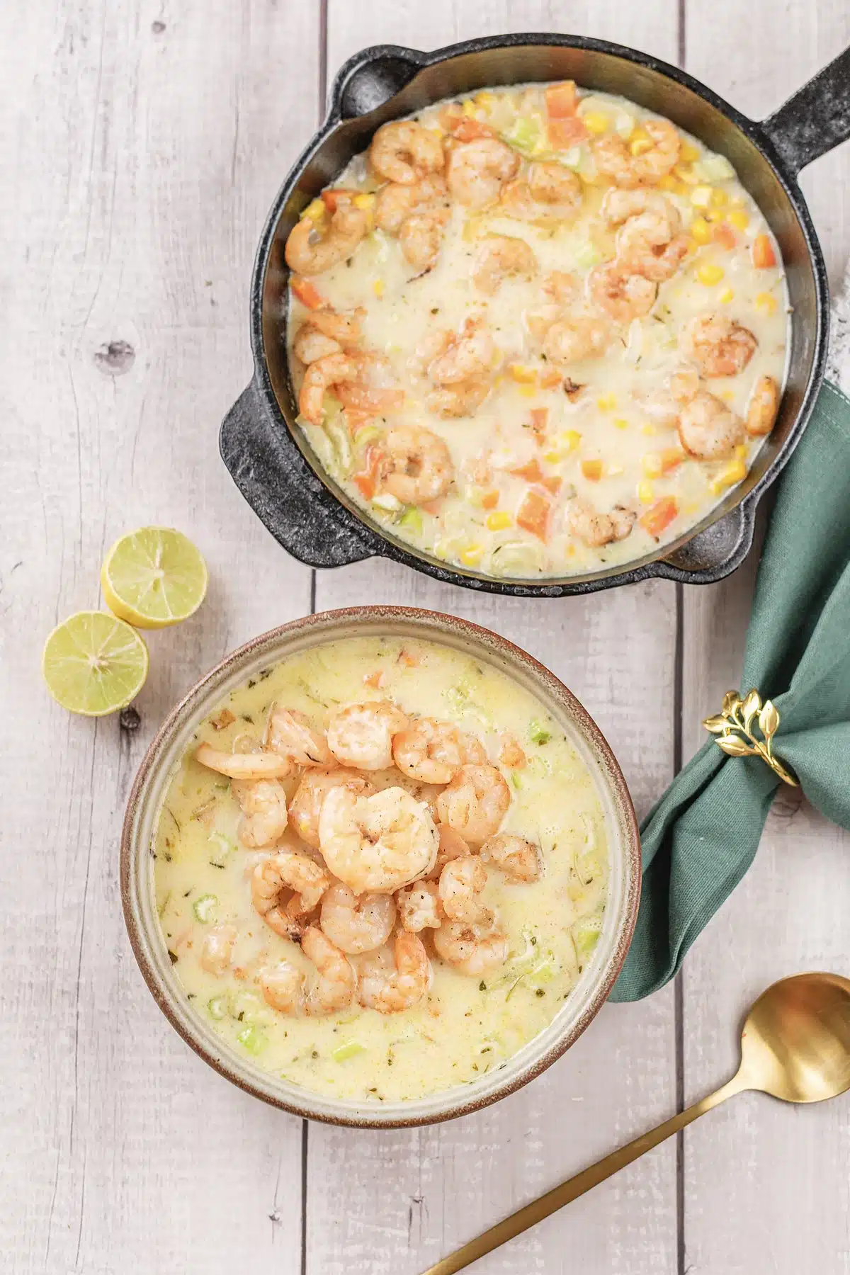 Shrimp chowder in a stoneware bowl with a small skillet and a halved lime