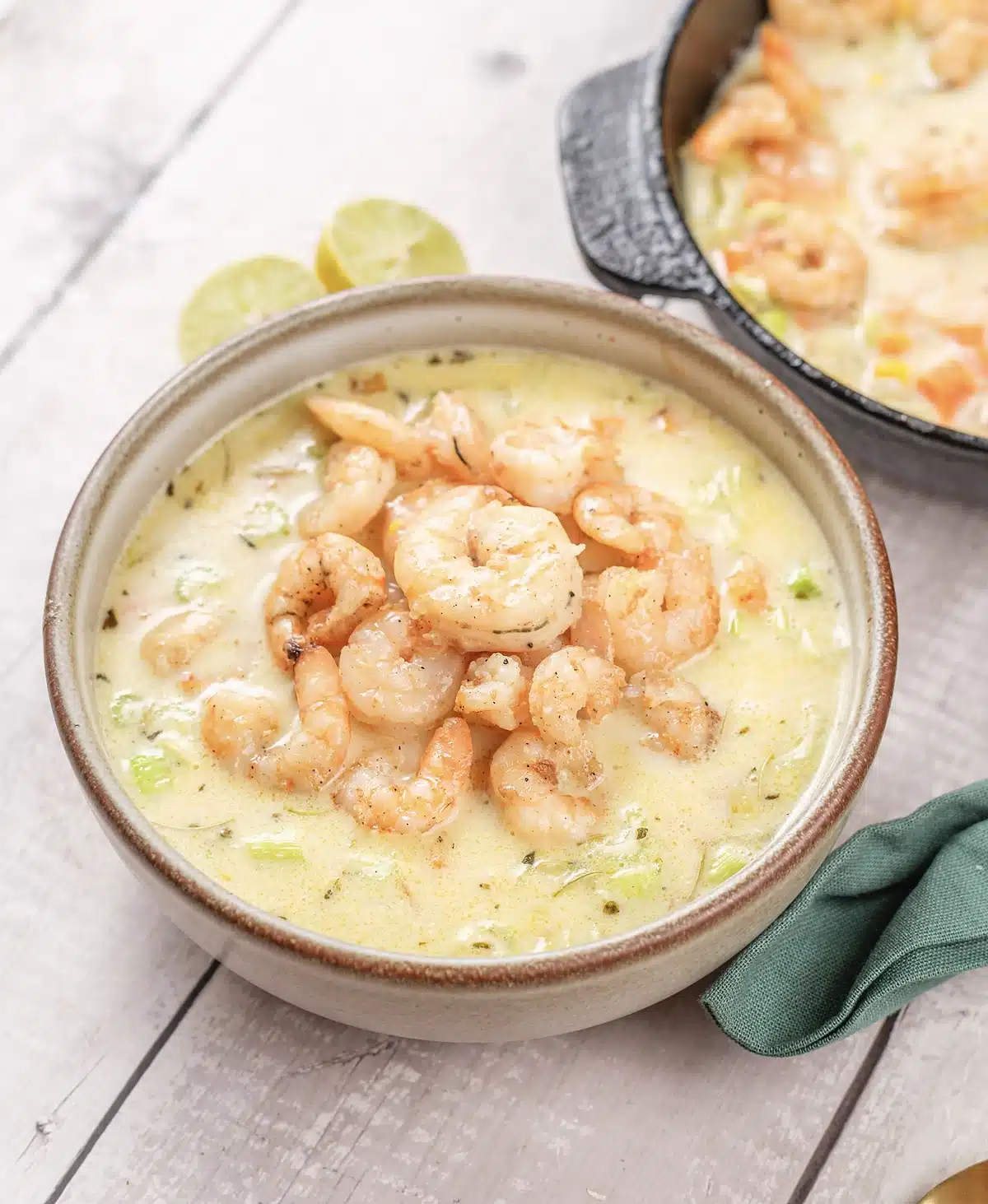 Shrimp chowder in a wide bowl with celery and diced carrot showing through