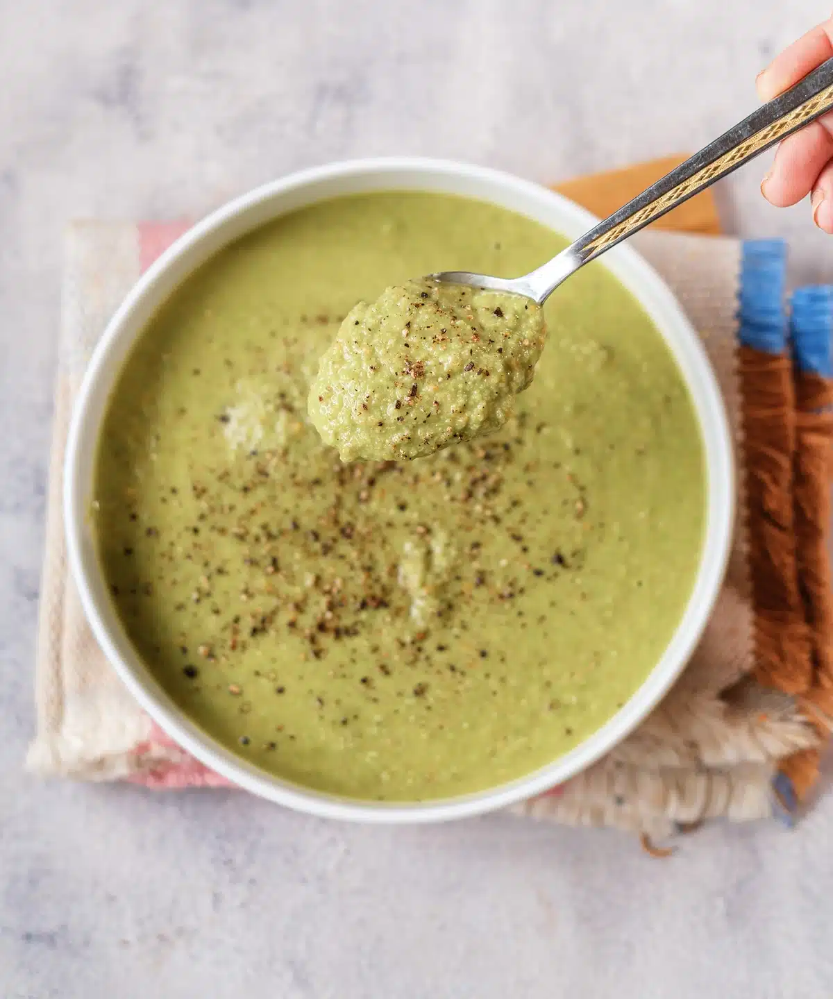 Green pea soup, the quick version of this split pea soup, lifted on a spoon from a white bowl