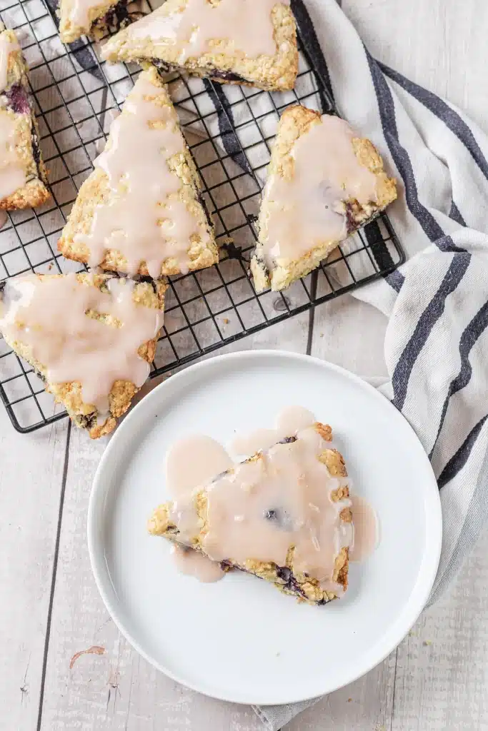 Blueberry scones seen from directly above with one glazed wedge on a white plate