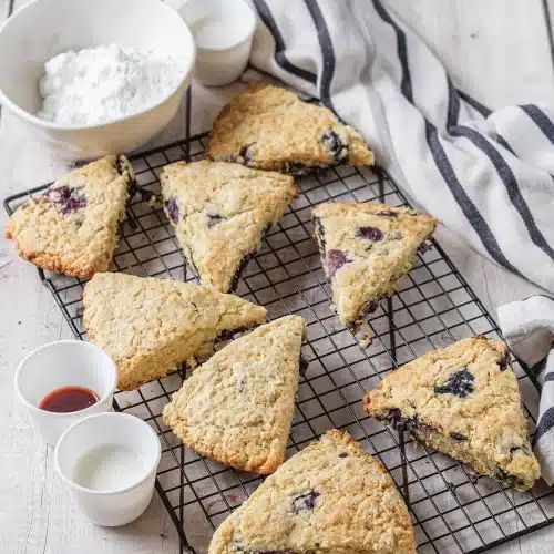 Baked wedges cooling on a black rack beside a bowl of powdered sugar