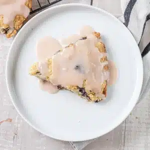 A single glazed blueberry scone on a small white plate
