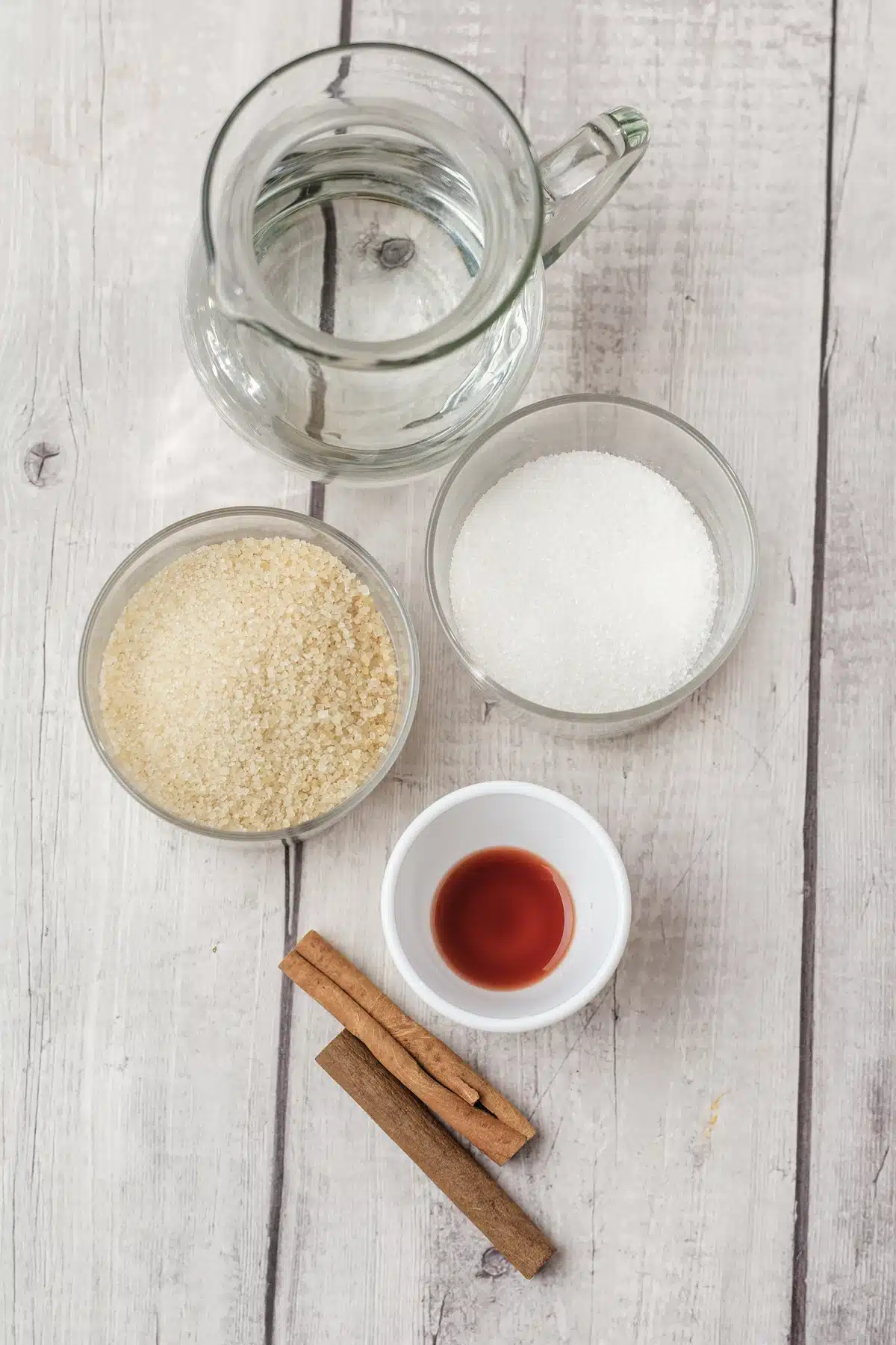 Water, brown sugar, granulated sugar, vanilla extract and cinnamon sticks laid out for the cinnamon dolce syrup