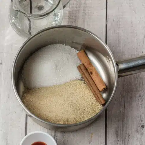 Brown sugar, white sugar and a cinnamon stick in a small saucepan