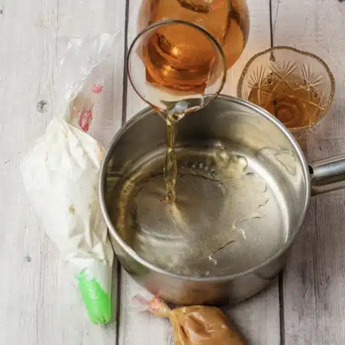 Juice poured from a glass pitcher into a saucepan to warm