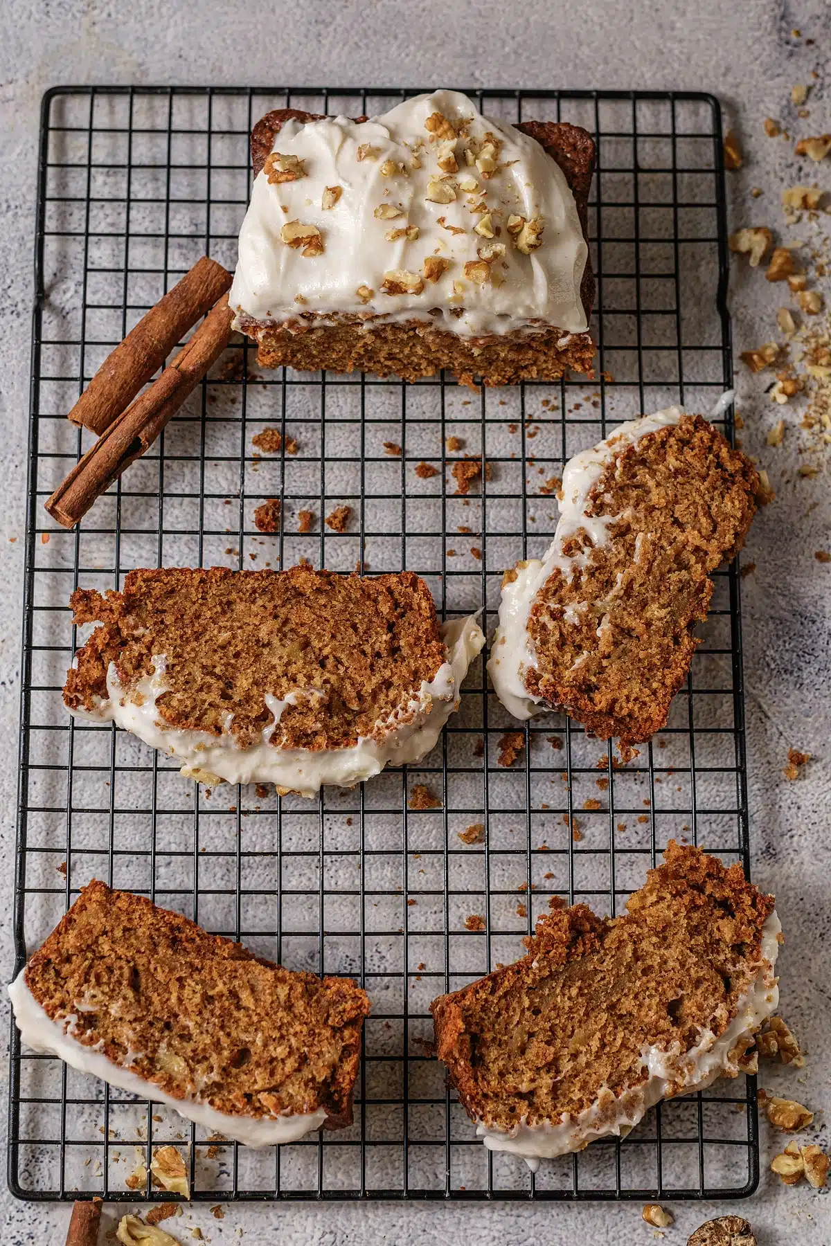 Overhead view of frosted slices and a cinnamon stick scattered across a cooling rack
