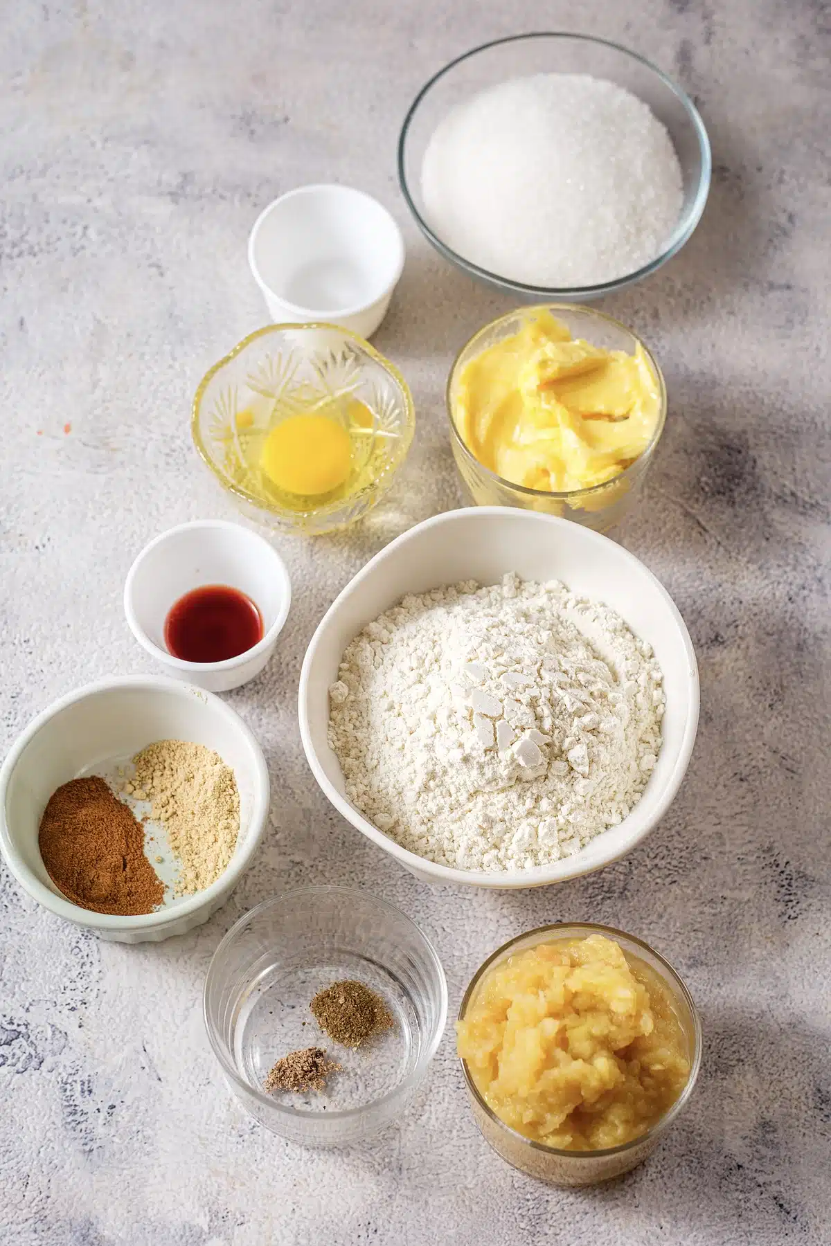 Butter, sugar, egg, flour, warm spices and applesauce measured out for gingerbread loaf