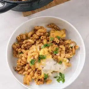 A single bowl of homemade beefaroni with melted cheese and parsley