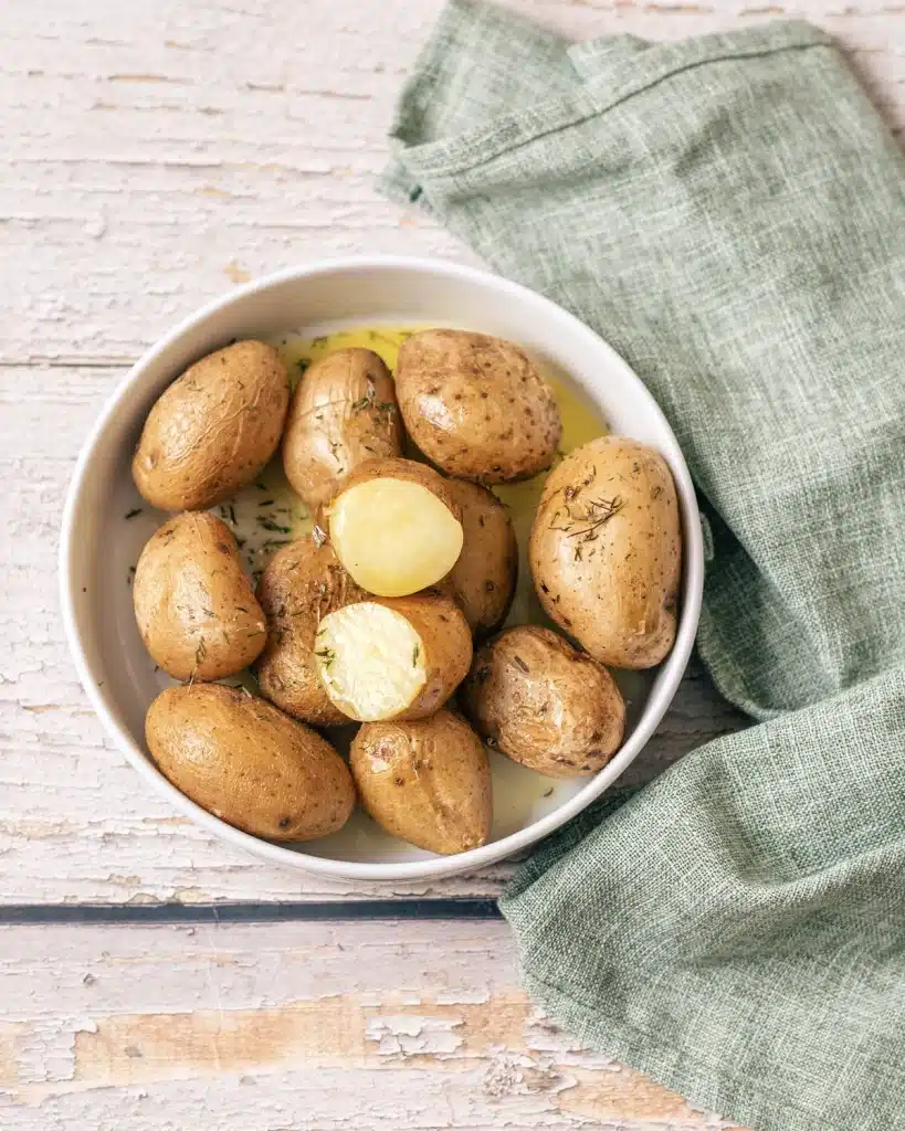 Syracuse salt potatoes in a white bowl with melted butter and thyme, seen from directly above