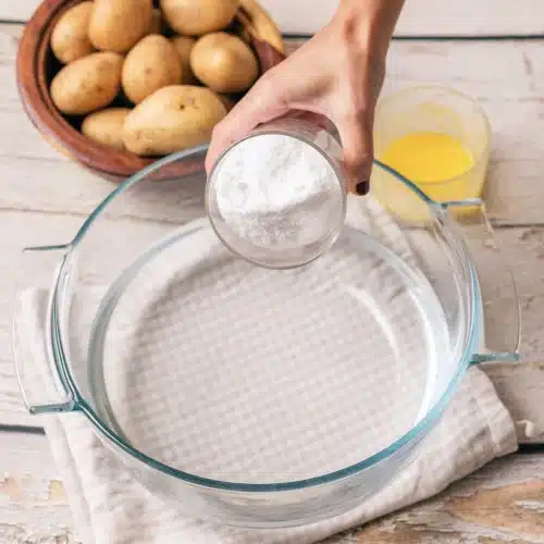 Fine salt poured from a small dish into a round glass dish of water