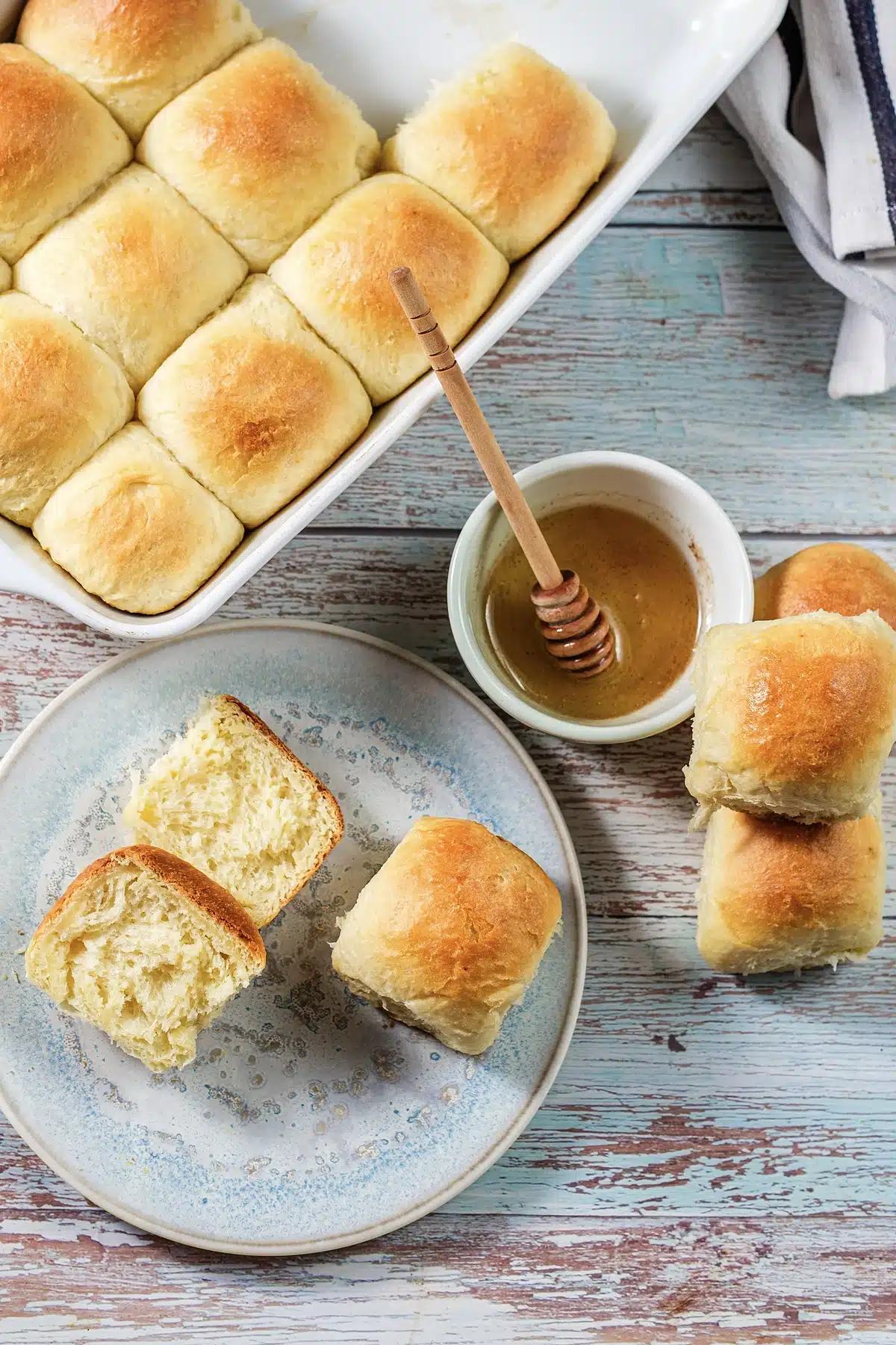 Texas Roadhouse rolls in a white dish with honey and a wooden dipper alongside