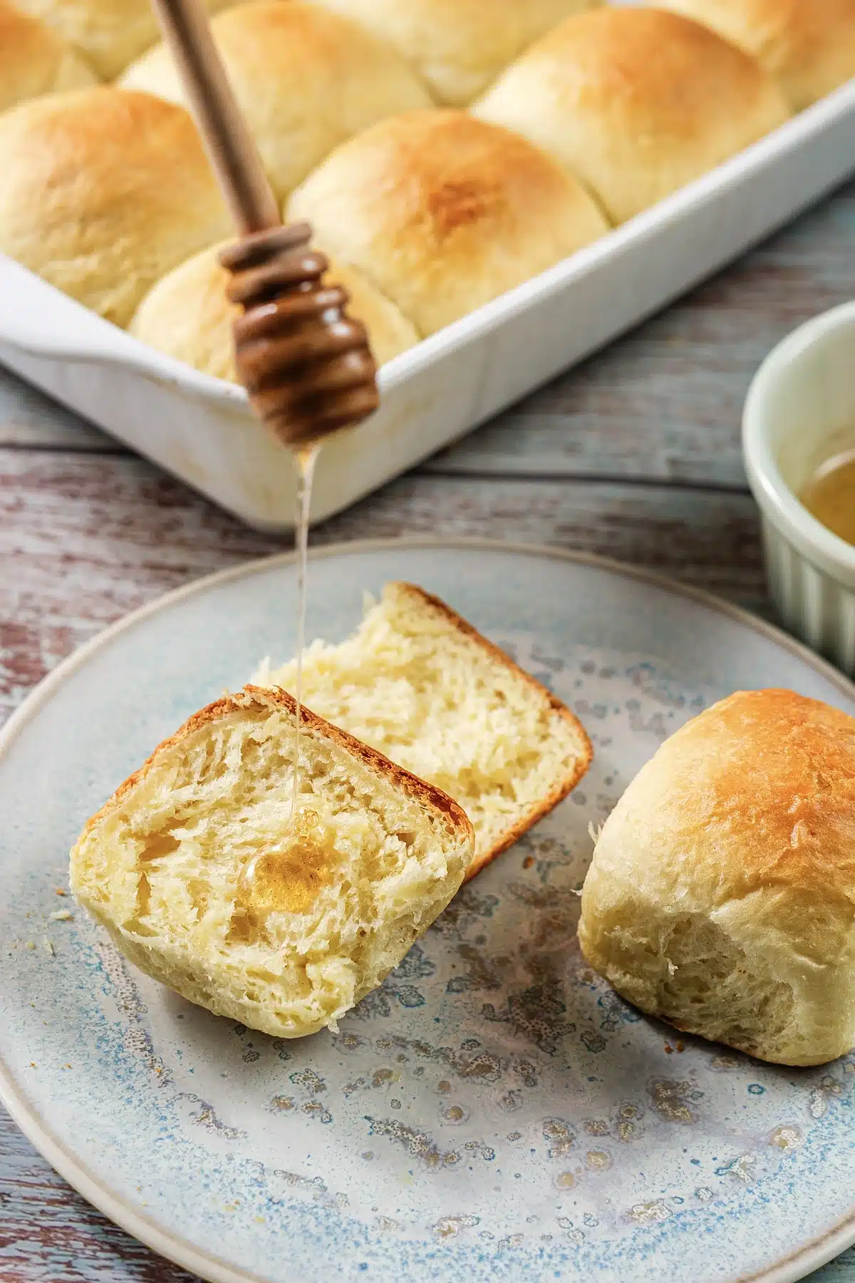 Texas Roadhouse rolls, one halved and glossy where the honey has soaked in