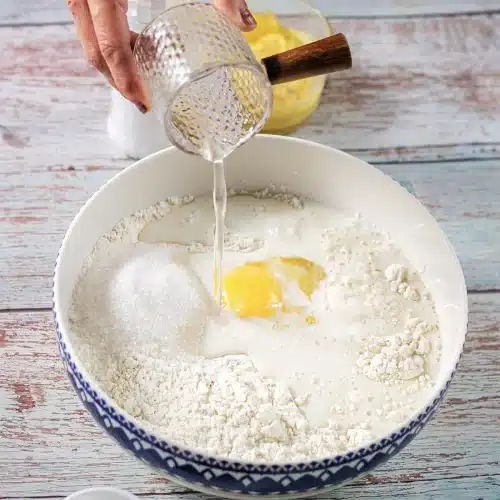 Warm liquid poured from a glass into the flour and sugar