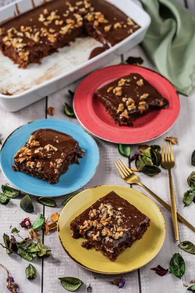 Texas sheet cake in its pan with three plated squares seen from directly above