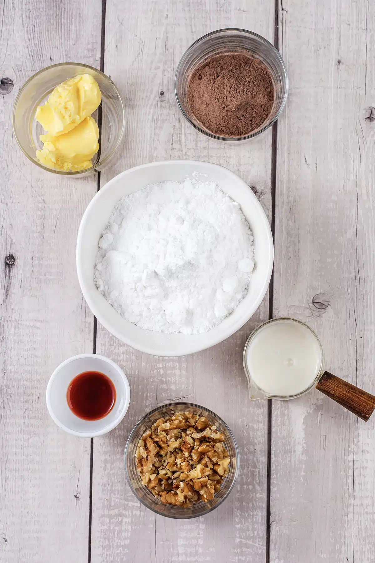 Butter, cocoa, powdered sugar, milk, vanilla and walnuts laid out for the icing