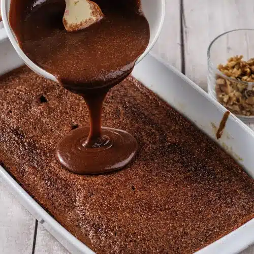 Warm fudge icing poured over the cake straight from the oven