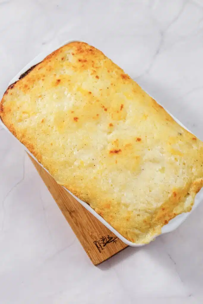 Chicken cobbler seen from directly above, golden and set in a white dish on a board