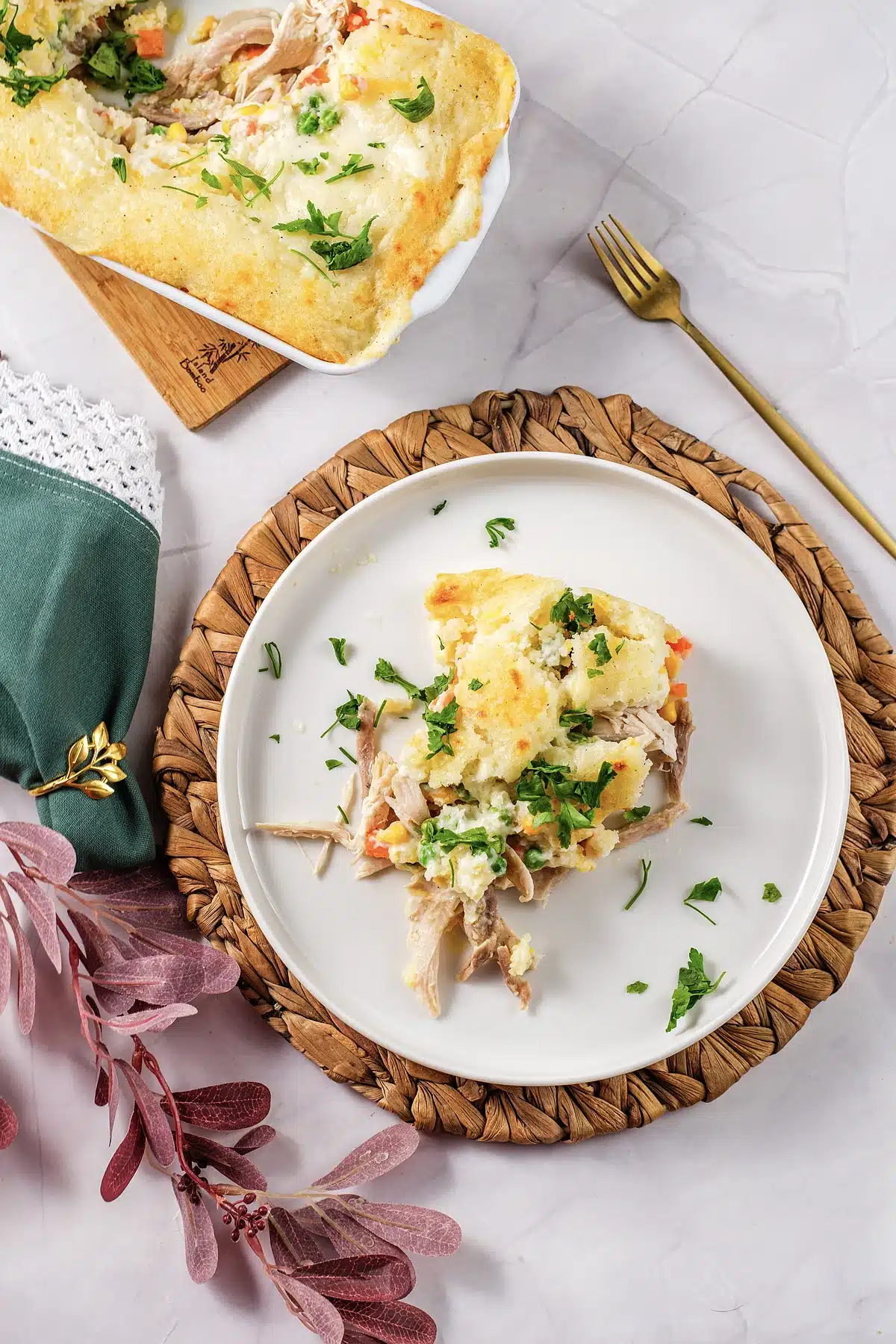Chicken cobbler served onto a white plate with the baking dish behind