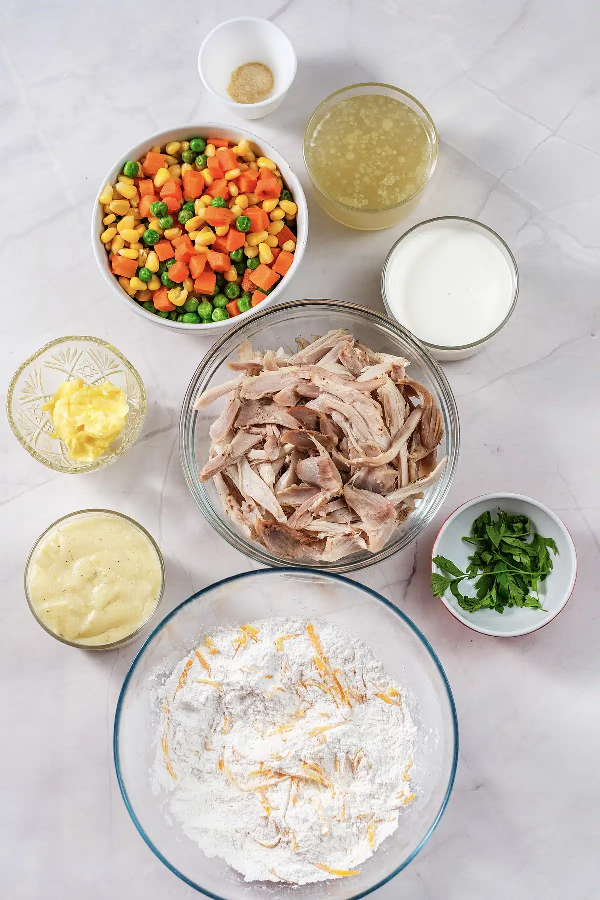 Mixed vegetables, broth, milk, butter, shredded meat and biscuit mix in bowls