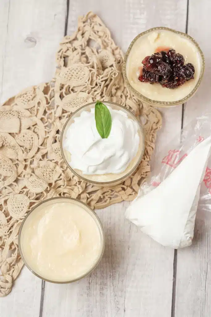 Homemade vanilla pudding in glasses seen from directly above, one topped with whipped cream and a mint leaf