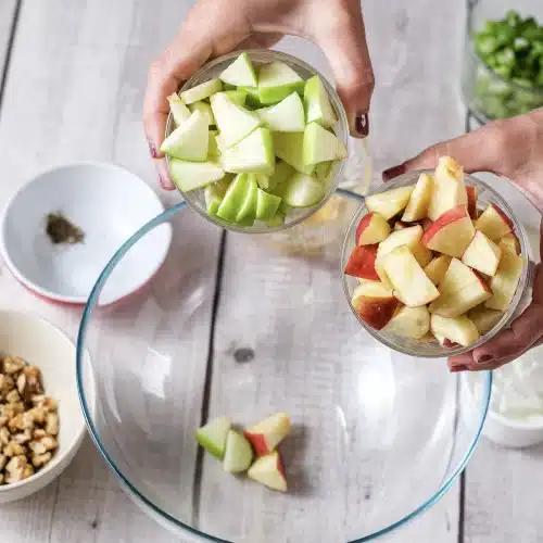 Diced green and red apple tipped from a glass into the mixing bowl