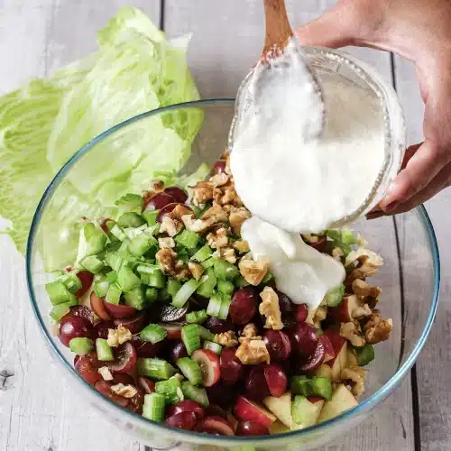 The creamy dressing poured from a bowl over the assembled fruit