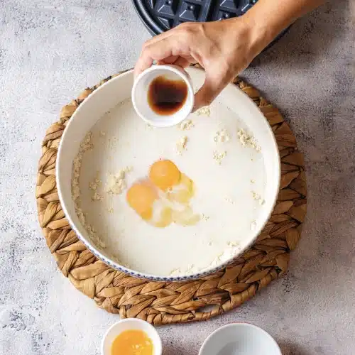 Vanilla poured from a small cup into the batter bowl