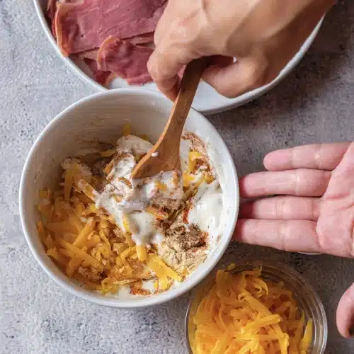 The sauce stirred with a wooden spoon until the cheddar and spices are mixed through
