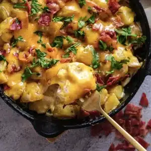 A spoonful of cheesy ranch potatoes with melted cheddar lifted from the skillet