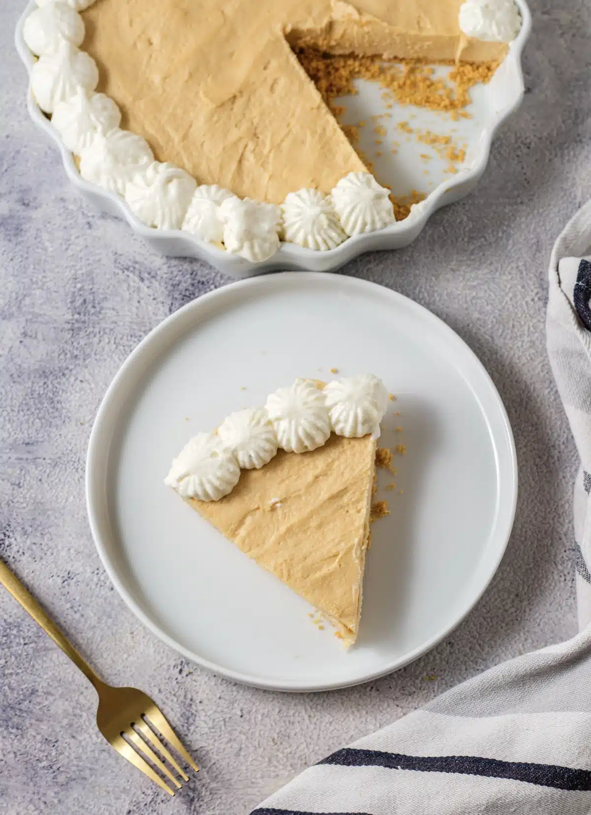 A slice of Dolly Parton's peanut butter pie on a white plate, with the rest of the pie in a fluted dish behind it