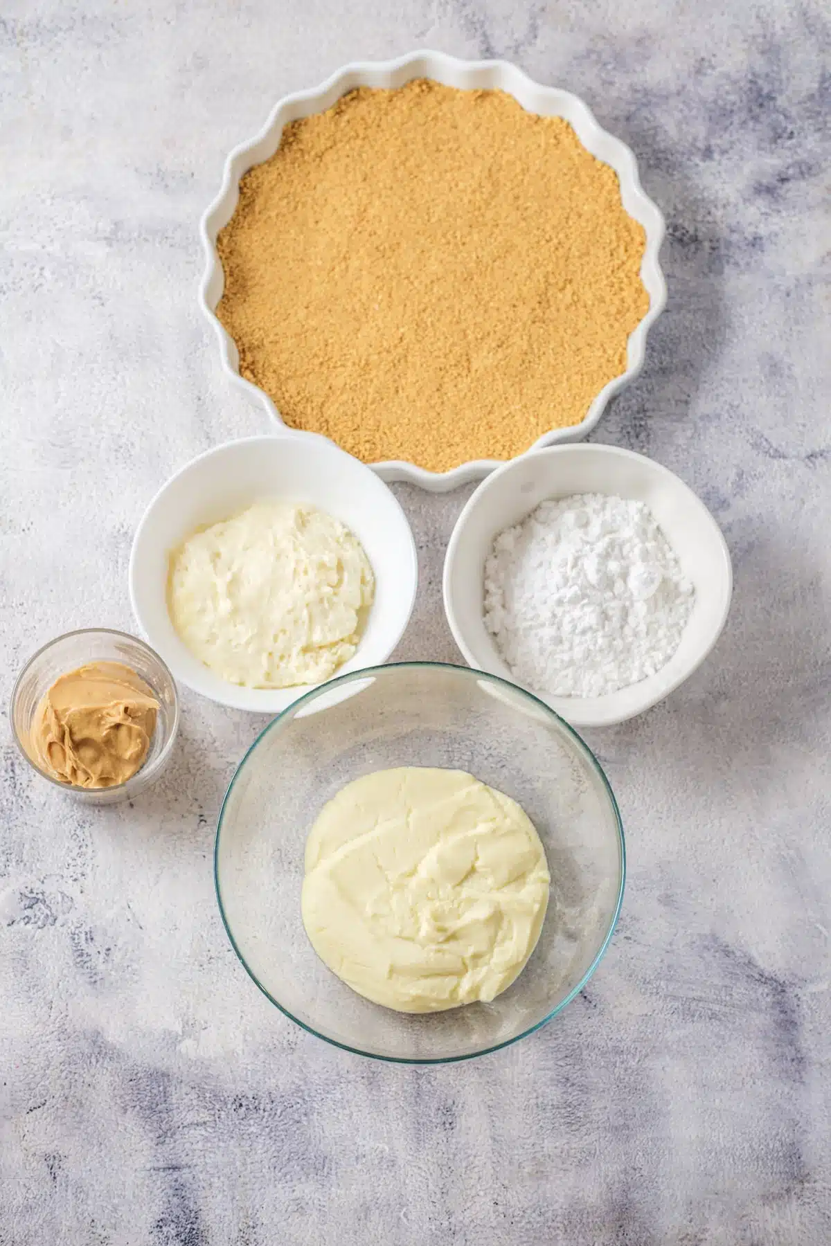 Ingredients for peanut butter pie: a graham cracker crust, cream cheese, powdered sugar, creamy peanut butter and whipped topping