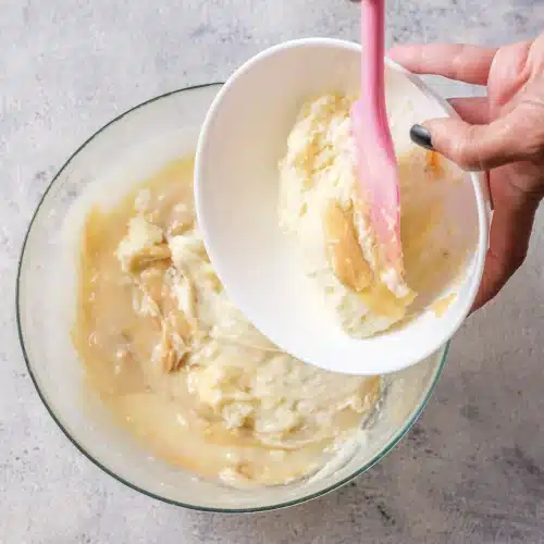 Whipped topping tipped from a white bowl into the filling and folded through with a spatula
