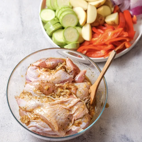 Raw thighs tossed in the marinade with a wooden spoon