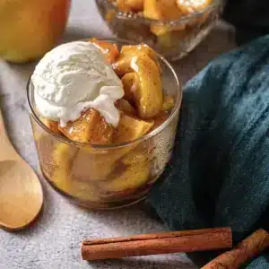 A single glass of microwave baked apples topped with a scoop of vanilla ice cream