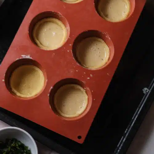 The pastry cups in the silicone mold filled three-quarters full with custard