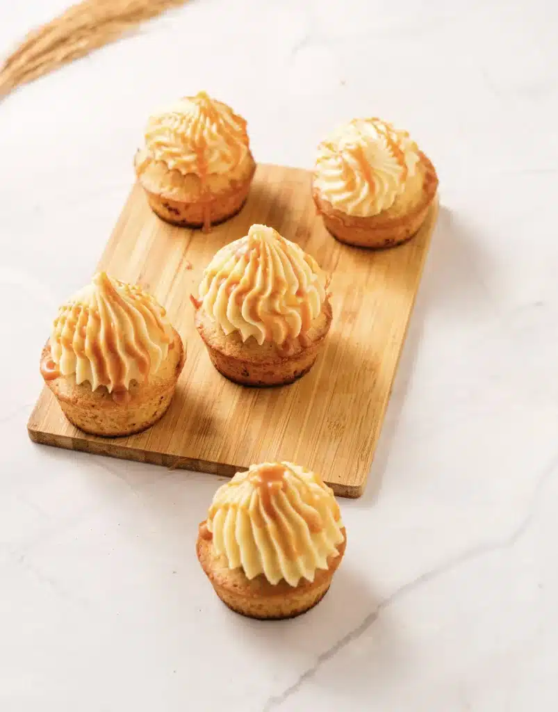 Salted caramel cupcakes on a bamboo board, seen from directly above, with tall swirls of caramel buttercream