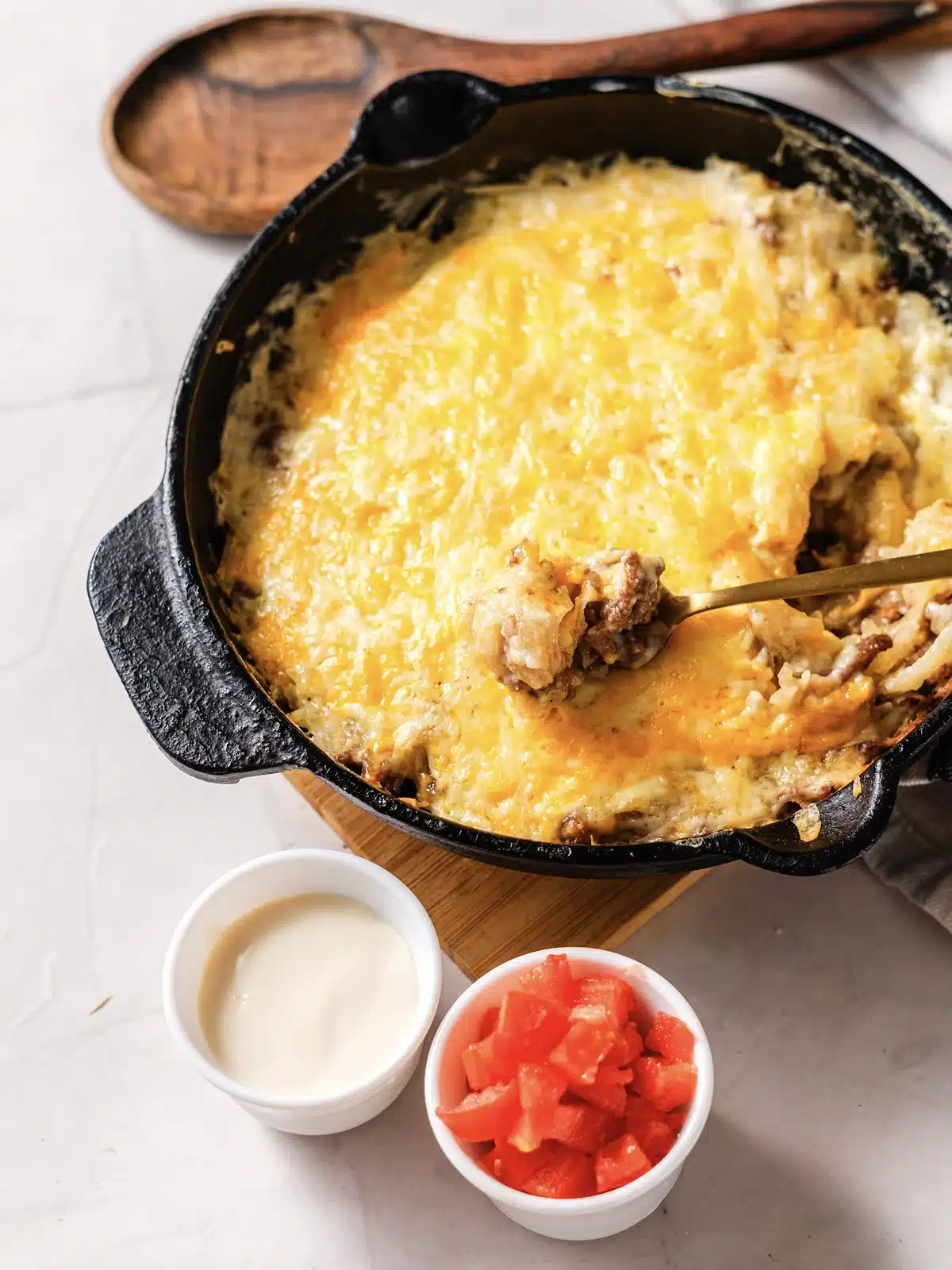 A spoonful of beef, potato and melted cheddar lifted over the skillet