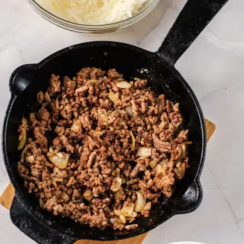 The beef browned and crumbled with the onion in the skillet