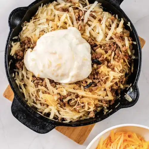 Sour cream spooned onto the beef and hash browns before folding